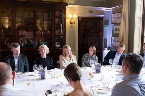 Five attendees at the roundtable face the camera, engaging in a discussion around insurance fraud with other delegates.